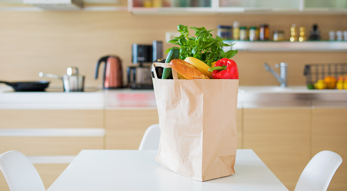 Paper shopping bag full with groceries products on kitchen table