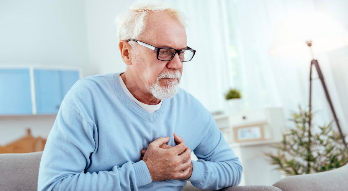 Attentive senior man holding chest and wearing glasses